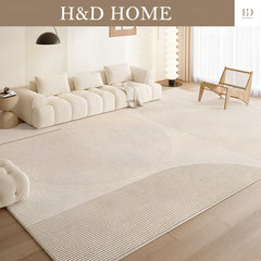 Living room with a large beige rug, white sofa, and wooden chair, featuring H&D Home branding.